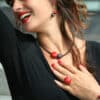 Bijou artisanal en céramique couleur cerise sur une main